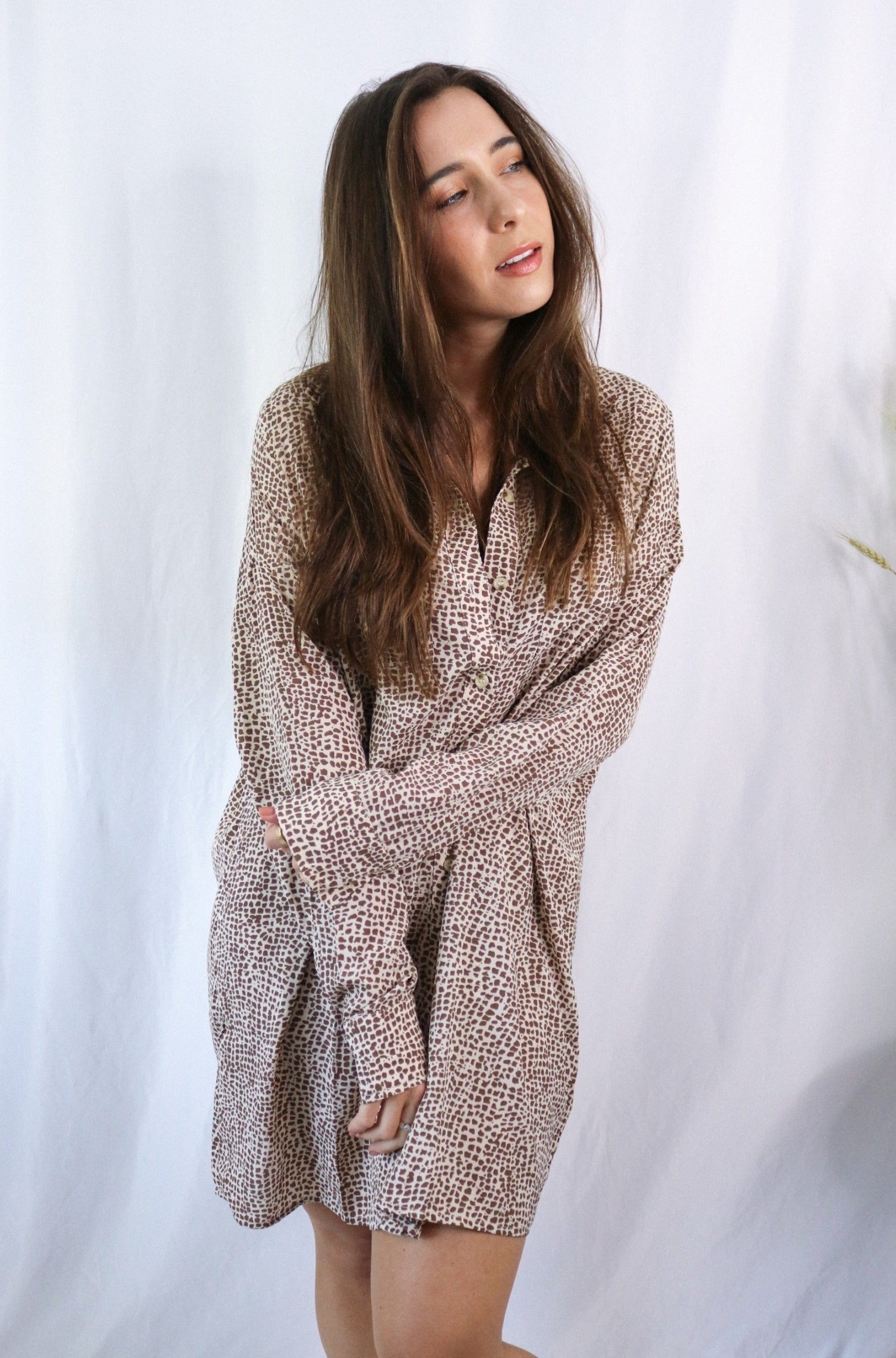 Brunette girl models a collared T-Shirt Dress in Animal Print (cheetah / leopard print). The t-shirt dress is collared, brown, and mid-length. It is a long sleeve t-shirt dress with a loose and comfortable fit.