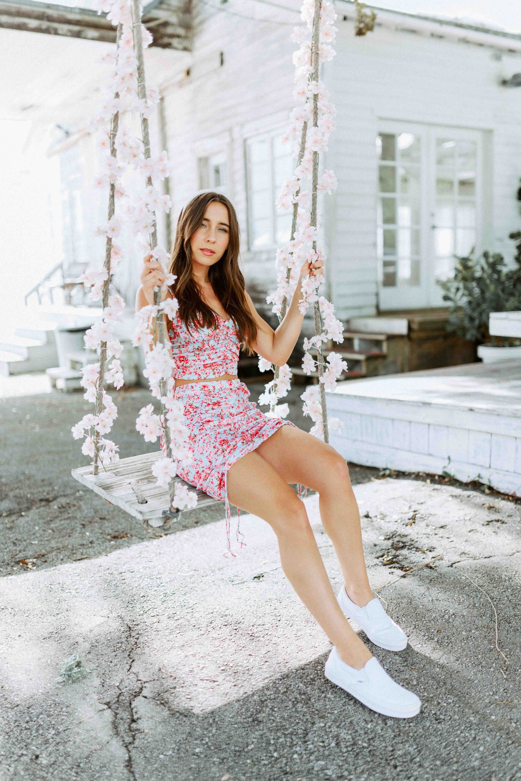 Brunette modeling a floral print matching mini scrunch skirt set in light blue and pink for Scarlette The Label, an online fashion boutique for women.